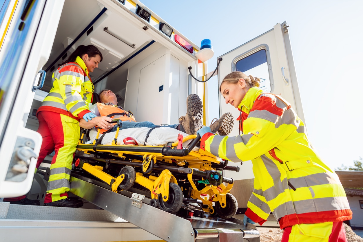 Sanitäter in Uniform setzen verletzten Mann auf Trage im Krankenwagen