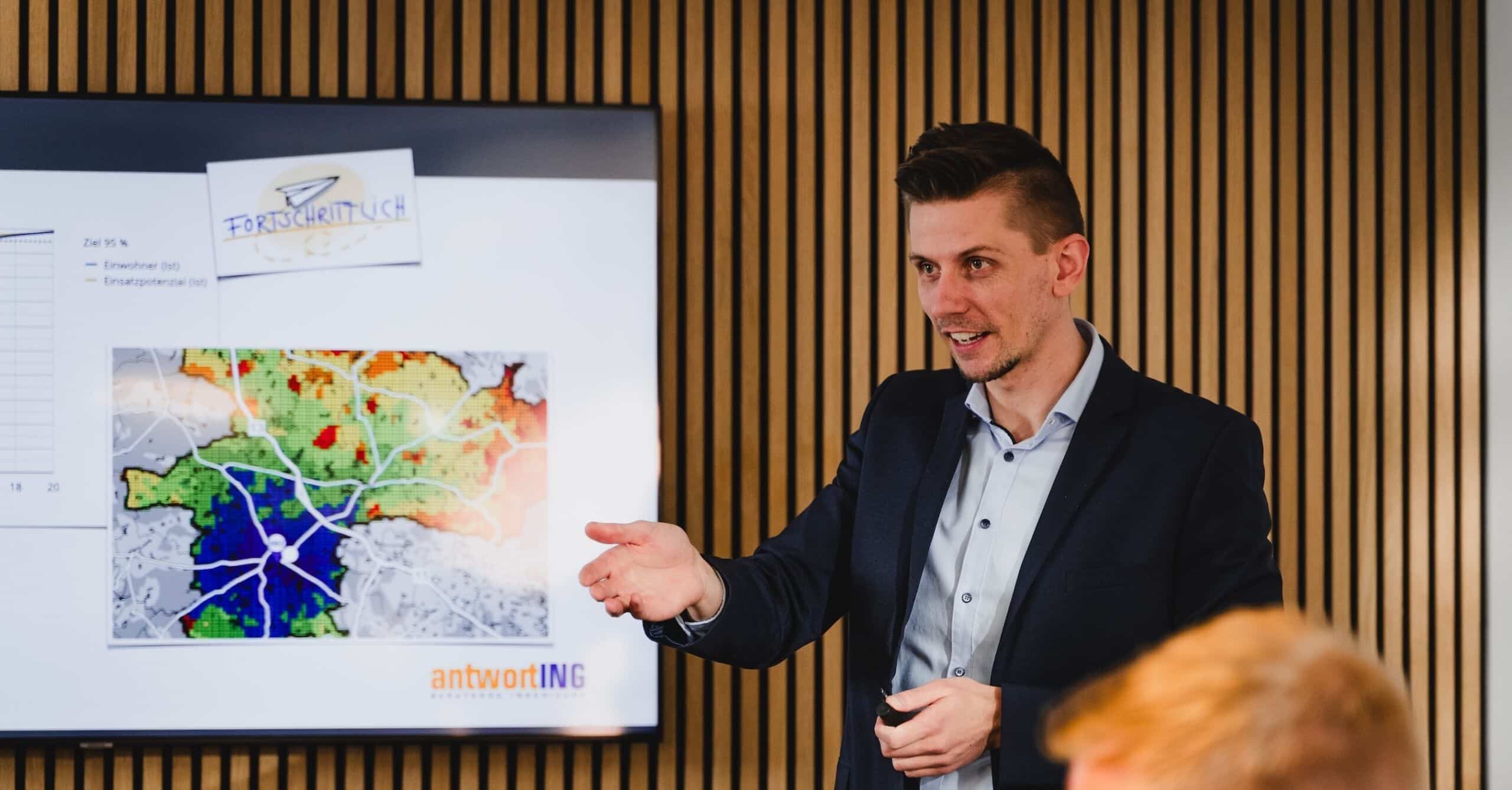 Mann präsentiert Analysekarte mit Einsatzpotenzialen vor Bildschirm mit antwortING-Logo im Konferenzraum.